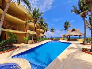 a swimming pool in front of a building with palm trees at Villa 301, Ground floor, Oceanfront! in Mahahual