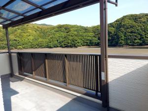 a balcony with a view of a river and trees at Guest House REMIKA in Saikai