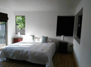 a white bedroom with a bed and two windows at Umawtu Bed and Wine in Casablanca