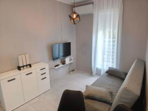 a white living room with a couch and a tv at Apartmani Trastevere Sombor in Sombor