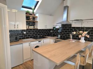 a kitchen with white cabinets and a wooden counter top at The Mews, Whetstone in Leicester