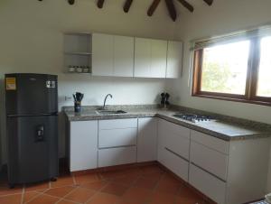 Una cocina con gabinetes blancos y un refrigerador negro. en Casa María Trinidad, en Villa de Leyva 2 fotos más