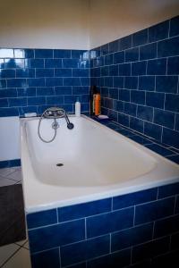 a bath tub in a blue tiled bathroom at maison bourgeoise in Rouffignac