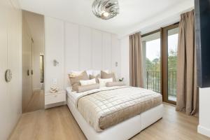 ein weißes Schlafzimmer mit einem großen Bett und einem Fenster in der Unterkunft Loft Premium Apartments by Baltic Home in Świnoujście + 92 Fotos