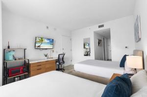 a hotel room with two beds and a tv at Modern New Studio Balcony & Pool in Hallandale Beach