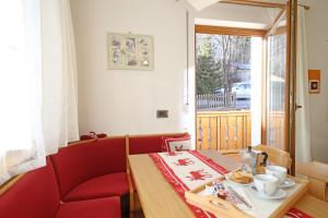 a room with a table and a red chair and a window at Ciasa Rudiferia Appartamenti in Alta Badia in Badia
