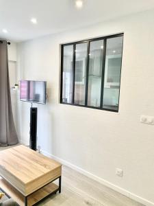 un salon avec une table et une télévision au mur dans l'établissement ChicCosy Studio 2mn RER proche Paris Aéroport Cdg - Supermarché en bas immeuble, à Villepinte