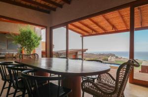 a table and chairs on a balcony with a view of the ocean at Casa Kahu by Wynwood House in Los Órganos
