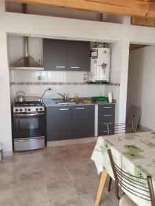 cocina con armarios grises, mesa y fogones en Departamentos Caracol, en Las Grutas