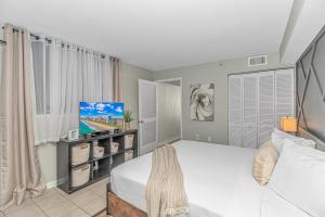 ein Schlafzimmer mit einem Bett und einem Flachbildfernseher in der Unterkunft Breathtaking Oceanfront Double Queen Suite! Meridian Plaza 701 - Perfect for 4 guests! in Myrtle Beach + 74 Fotos