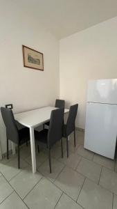a table with chairs and a white refrigerator in a room at Sweet Home in Santa Marinella +2 photos