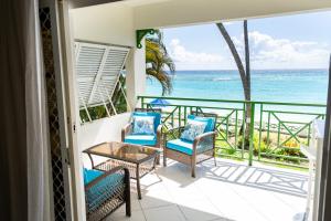 a balcony with chairs and a table and a view of the ocean at Sweet Life Condo in Bridgetown