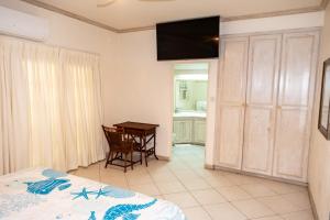 a bedroom with a bed and a table and a television at Sweet Life Condo in Bridgetown