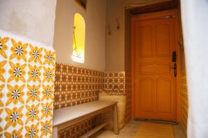 a bathroom with a orange door and a bench at Houch El Houdou in Tozeur
