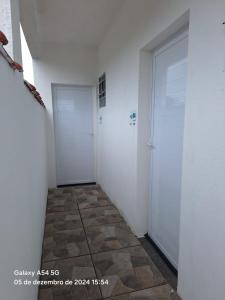 a hallway with two white doors and a tile floor at Casa da Maria Ubatuba in Ubatuba
