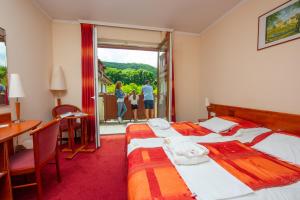 a hotel room with two beds and a desk and a balcony at Erzsébet Park Hotel in Parád