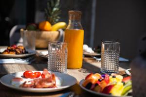 a table with plates of food and a bottle of orange juice at Nestor Luxury Villas in Romanu
