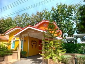 a yellow house with a tree in front of it at Felice House Khaoyai ฟิลิเช่เฮ้าส์เขาใหญ่ in Nong Nam Daeng