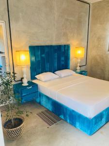 a bedroom with a blue bed with two night stands and a plant at WAVES Weligama in Weligama