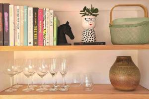 a shelf with wine glasses and a vase and books at Bakery Cottage Moyhu in Moyhu