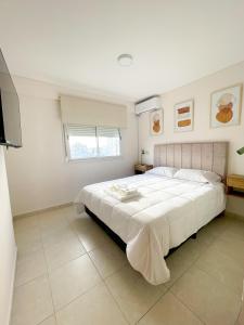 a bedroom with a large white bed and a window at Saavedra 118 6ºI by depptö in Bahía Blanca +7 photos