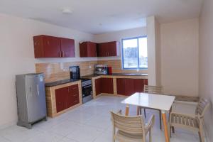 a kitchen with wooden cabinets and a table and chairs at 2 Bedroom Apartment in Links Road Nyali in Mombasa