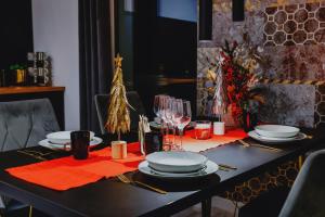 a black table with plates and glasses and a christmas tree at Nowoczesne Apartamenty typu Superior - Bulwary Rabka Zdrój - Balia - Blisko Park Zdrojowy in Rabka