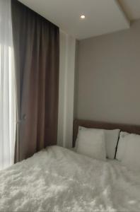 a bed with white sheets and pillows next to a window at Lola apartman Residence Hill in Kopaonik +8 photos