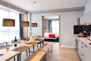 شقق ملوفت ميونيخ في ميونخ: مطبخ وغرفة طعام مع طاولات وكراسي خشبية