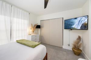 a white bedroom with a bed and a flat screen tv at Pompano Cove in Pompano Beach