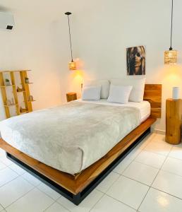 a bedroom with a large bed with white sheets at Encantador Loft con Piscina 1 BDR in Santa Teresa Beach