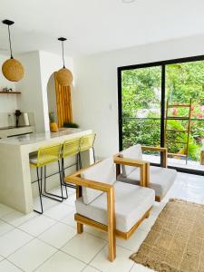 a kitchen and living room with yellow chairs and a table at Encantador Loft con Piscina 1 BDR in Santa Teresa Beach +5 photos