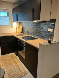a kitchen with black cabinets and a sink at Ferienwohnung an der Aitrach in Aitrach
