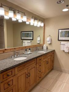 a bathroom with two sinks and a large mirror at The Grand Summit Hotel in the Canyons Village - Walk to Ski Lift - Pool, Gym, Spa, More! in Park City