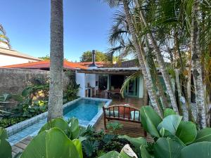 a villa with a swimming pool and palm trees at Guarda do Embaú Aluguél Casa 300mts Praia in Guarda do Embaú
