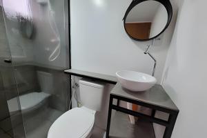 a bathroom with a toilet and a sink and a mirror at Chalé Henri Salvador na Vinícola Reconvexo in Morro do Chapéu