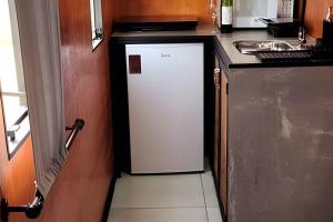 a small white refrigerator in a kitchen next to a counter at Chalé Henri Salvador na Vinícola Reconvexo in Morro do Chapéu