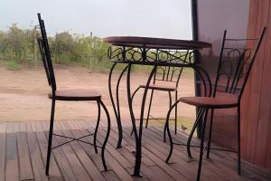 two chairs and a table and a table and two stools at Chalé Henri Salvador na Vinícola Reconvexo in Morro do Chapéu