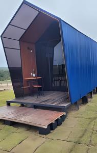 a house with a blue roof and a wooden deck at Chalé Henri Salvador na Vinícola Reconvexo in Morro do Chapéu