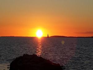 una puesta de sol con un velero en el océano en Ferienhaus "Sommerbrise", en Gager