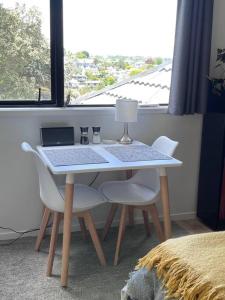 a table with two chairs and a laptop on it at The Aotearoa Room in Auckland +7 photos
