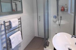 a white bathroom with a sink and a shower at The Aotearoa Room in Auckland