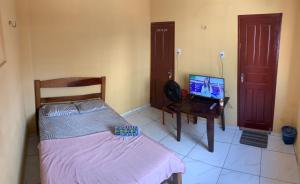 a bedroom with a bed and a desk with a computer at Carpe Diem Suítes in Belém