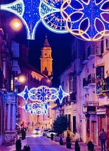 eine Stadtstraße mit Weihnachtslichtern und einem Uhrturm in der Unterkunft Casa Torre Hacho in Antequera