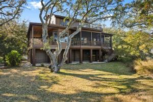 a large wooden house with a tree in front of it at Windows on the Water in Pawleys Island