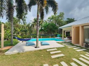 a hammock next to a house with a swimming pool at Villa Douce in Thongsala