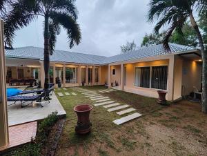 a house with a yard with a bench and palm trees at Villa Douce in Thongsala