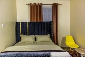 a bed in a room with a yellow chair at Cozy Haven in Juja