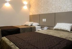 Una habitación de hotel con dos camas y un teléfono. en Hotel Caju de Ouro, en Feira de Santana