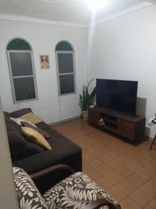 a living room with a couch and a flat screen tv at Casinha feliz in Guaratinguetá